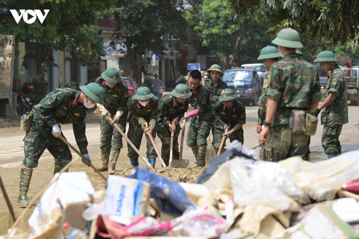 Bộ đội, sinh viên lấm lem bùn đất giúp người dân dọn dẹp bùn đất sau lũ