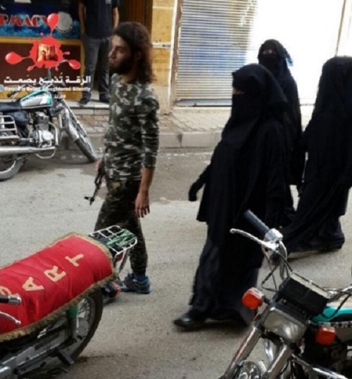 Một chiến binh IS ra đường cùng ba cô vợ trùm kín từ đầu đến chân hôm 6/11/2015. Phụ nữ tại Raqqa bị cấm ra đường một mình. Ảnh: RBSS